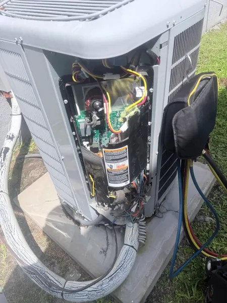 Inverter outdoor AC unit with its service panel removed, showing the electronic control board, compressor and wiring